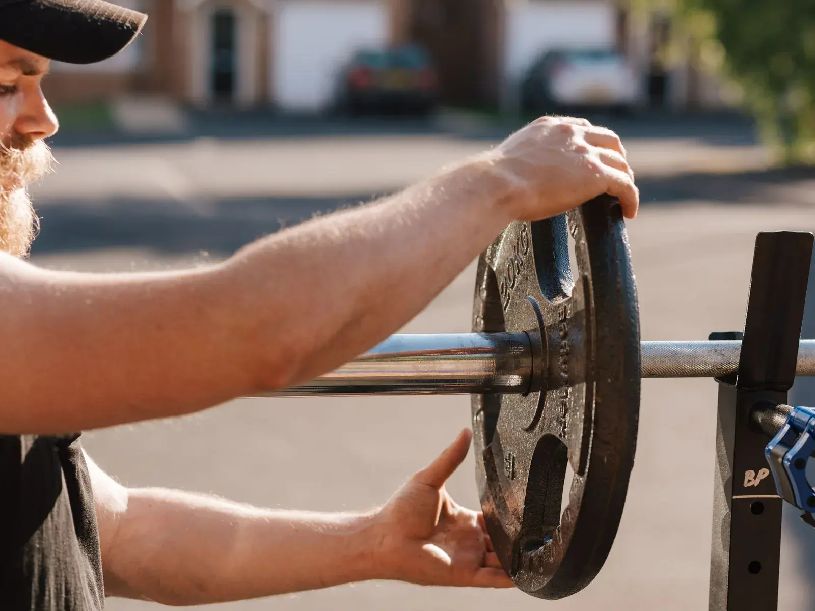 Entrenador personal añadiendo un disco de 1,25 kilos a la barra de su cliente